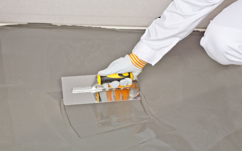 concrete-mixer-spreading-self-leveling-compound-with-trowel-min