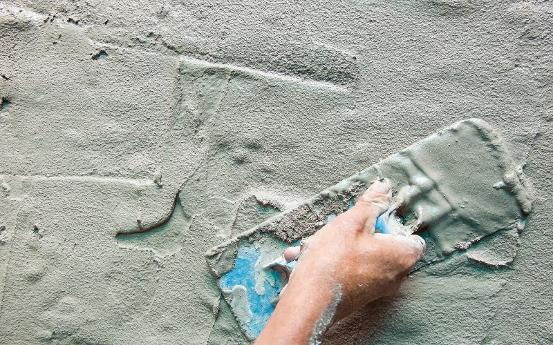 concrete-mixers-closeup-mason-hand-fresh-concrete-mix-with-trowe-min