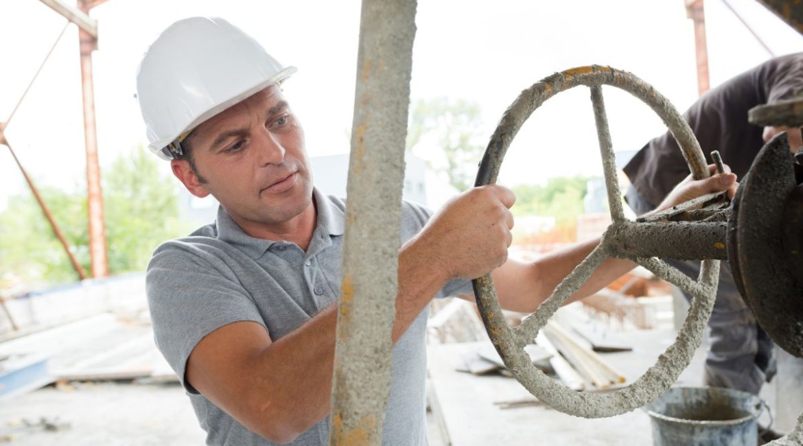 CONCRETE-MIXER-man-turning-wheel-to-tip-cement-from-mixer-min