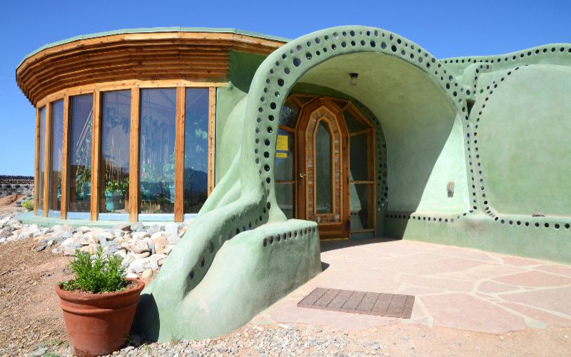 Concrete-mixer-entrance-of-an-earthship-sustainable-house-made-out-of-adobe-and-upcycled-glass-bottles-near-taos-in-new-mexico-usa-min
