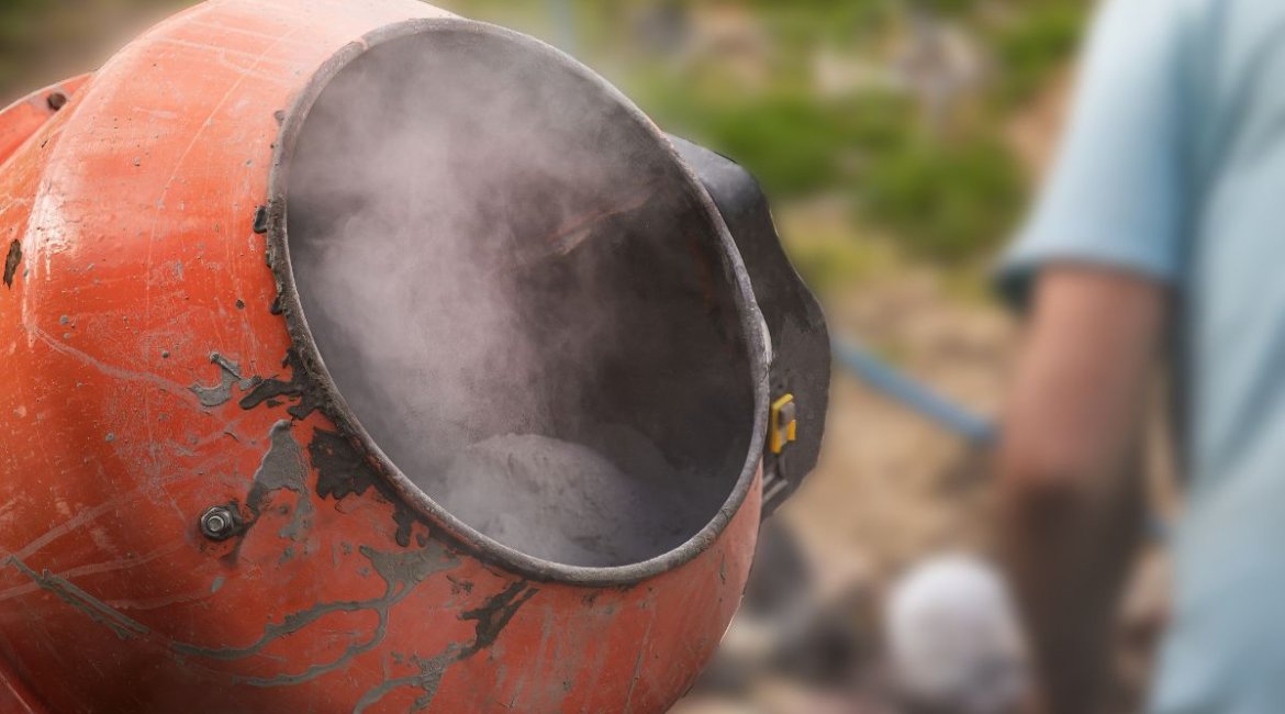 Concrete-mixer-old-red-cement-mixer-with-gray-dry-cement-powder-and-dust-during-mixing-process-min