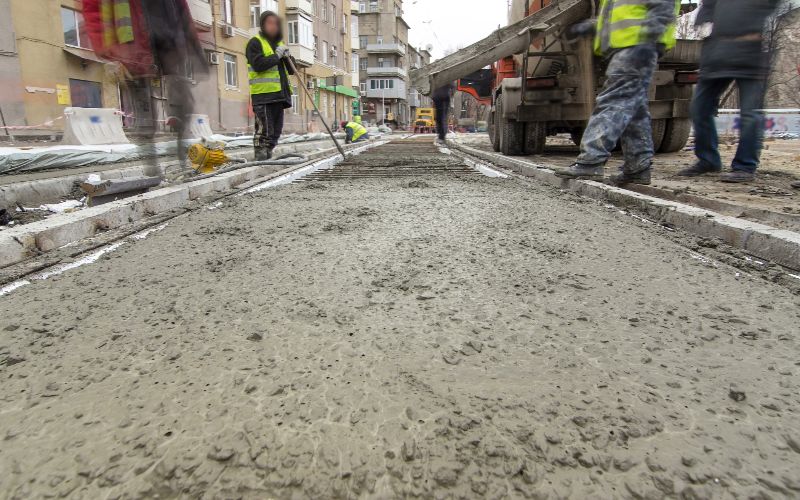 cement-mixers-pouring-ready-mixed-concrete-after-placing-steel-reinforcement-to-make-the-road-by-concrete-mixer-timelapse-hyperlapse-min