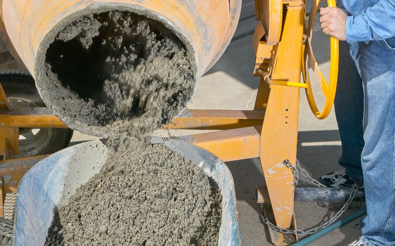 concrete-mixer-for-sale-worker-pouring-wet-cement-into-wheelbarrow-min