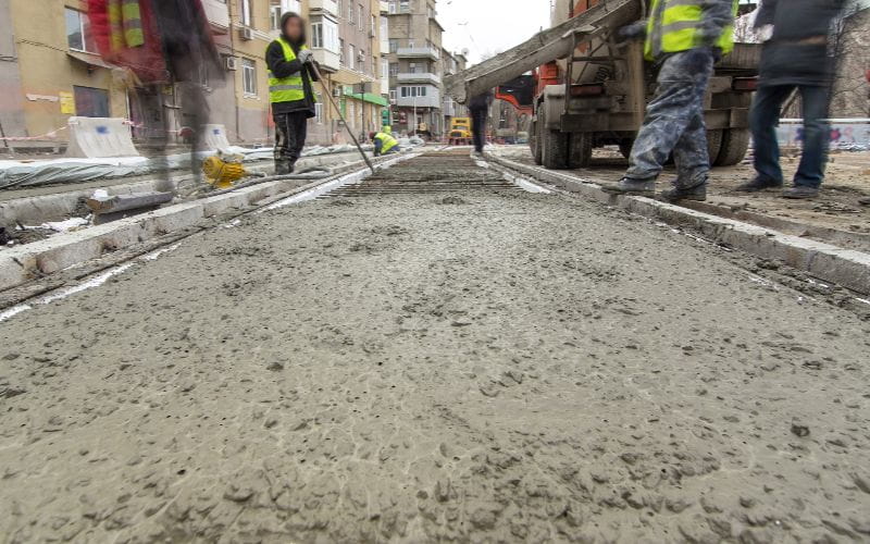 cement-mixers-pouring-ready-mixed-concrete-after-placing-steel-reinforcement-to-make-the-road
