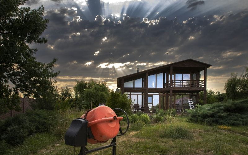 concrete-mixer-for-sale-modern-wooden-house-with-cement-mixer-at-sunset-under-dramatic-cloudy-sky