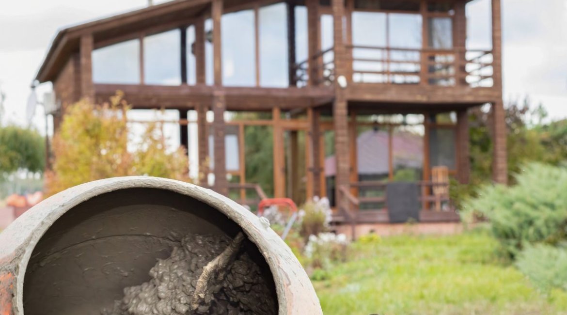 concrete-mixer-for-sale-old-cement-mixer-with-dried-concrete-positioned-in-garden-area-near-wooden-house