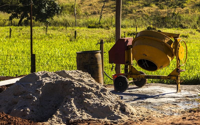 concrete-mixers-yellow-concrete-mixer-in-a-rural-setting-with-sand-pile (1)