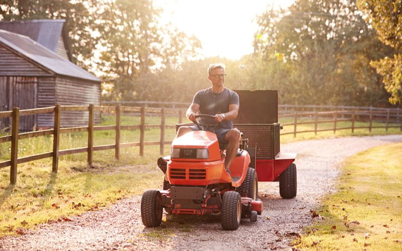 ride-on-mower-mature-man-driving-ride-on-mower-along-garden-path