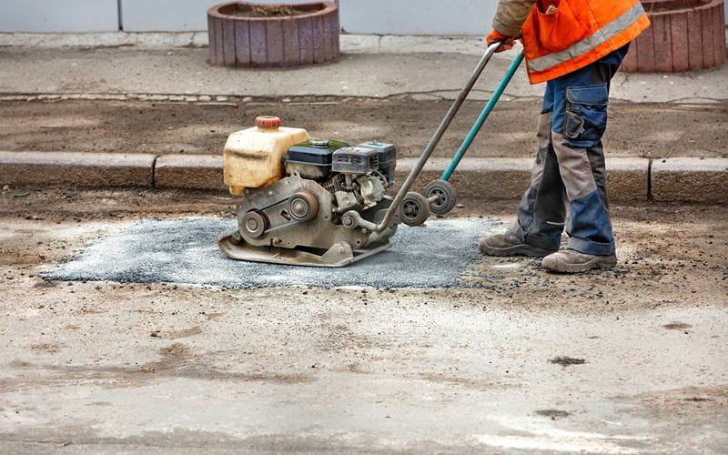 rammers-a-worker-with-a-petrol-vibrating-plate-patches-a-pothole-on-an-old-road (1)